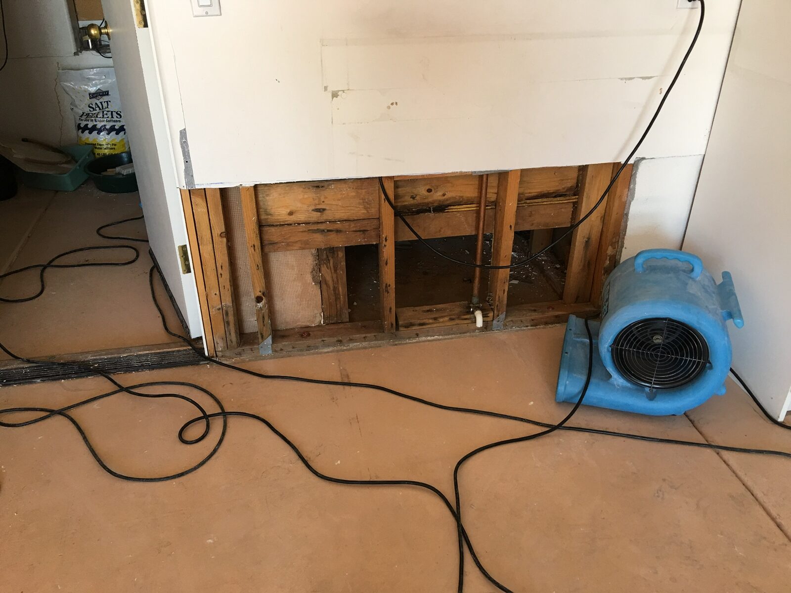 Air mover drying exposed wall framing where lower drywall was removed