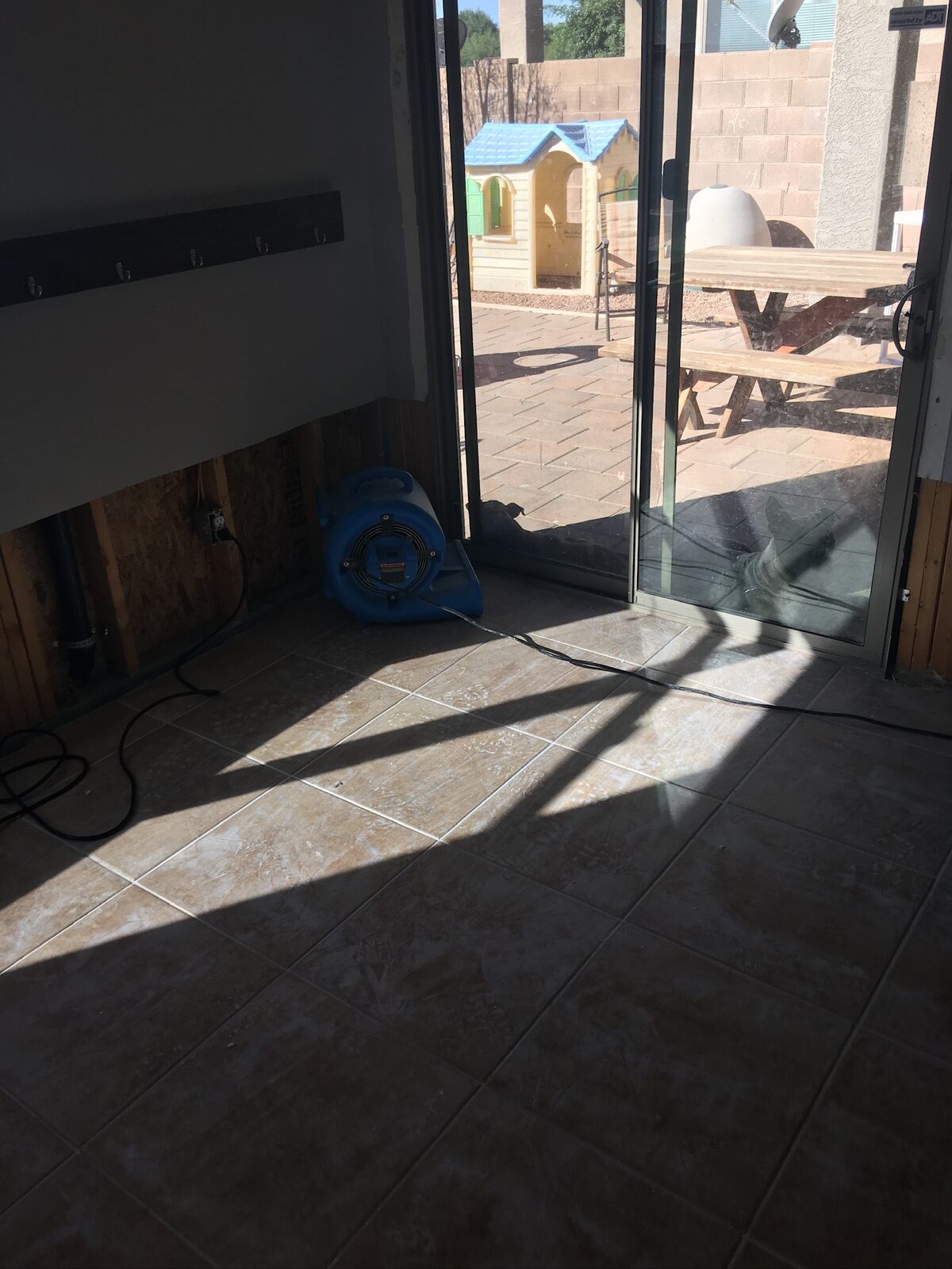Air mover drying a flood cut wall beside a sliding glass patio door
