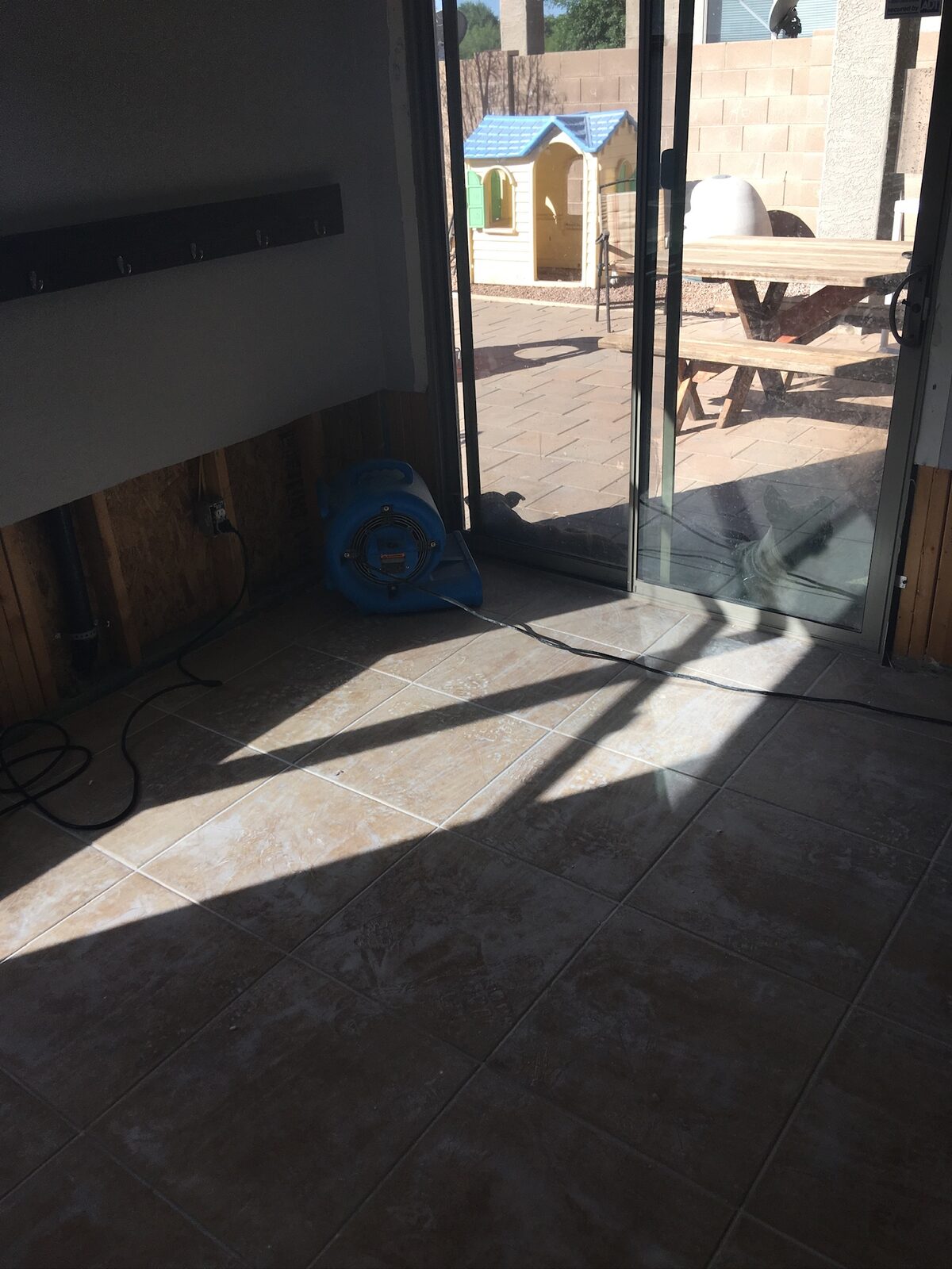 Air mover drying a wall with lower drywall removed near a sliding glass door