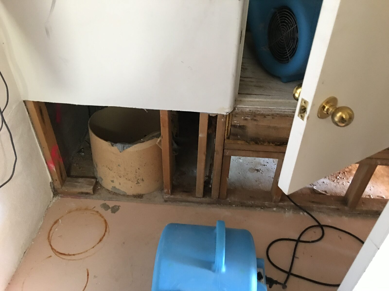Air movers positioned at an opened wall with exposed framing during water damage drying