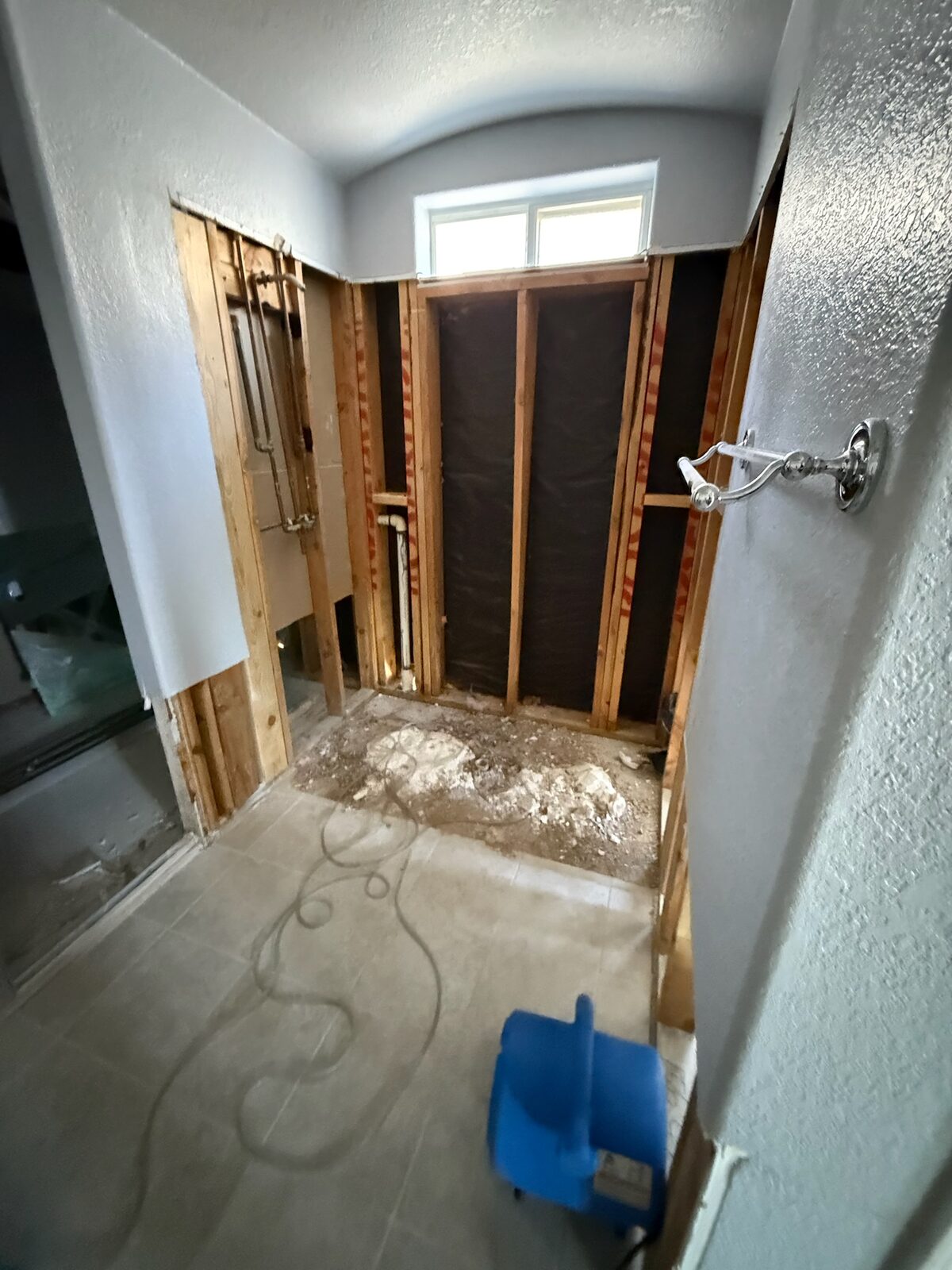 Bathroom demolished to framing with moisture barrier visible behind the shower wall