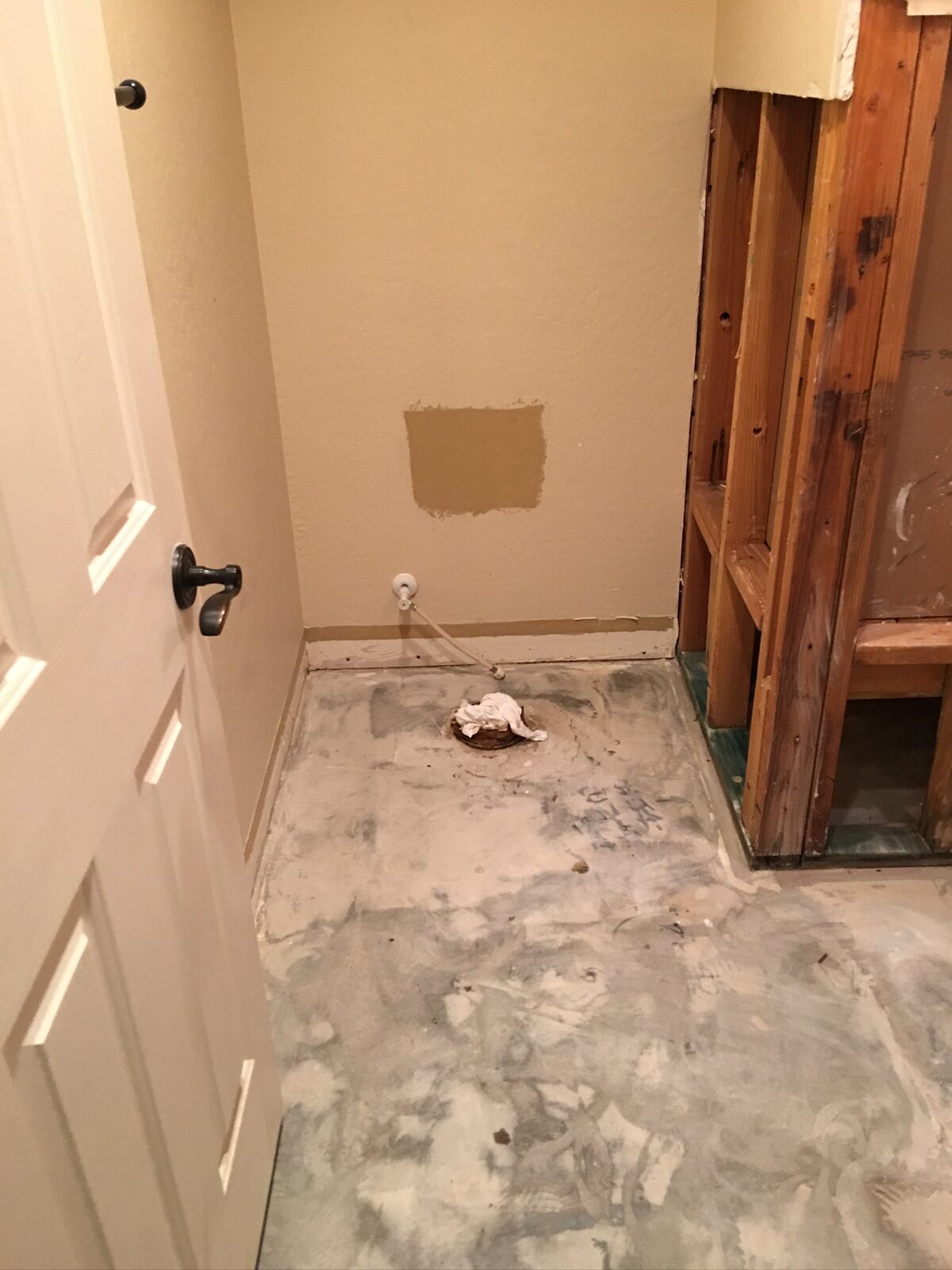 Bathroom with toilet removed showing a capped floor flange and exposed wall framing