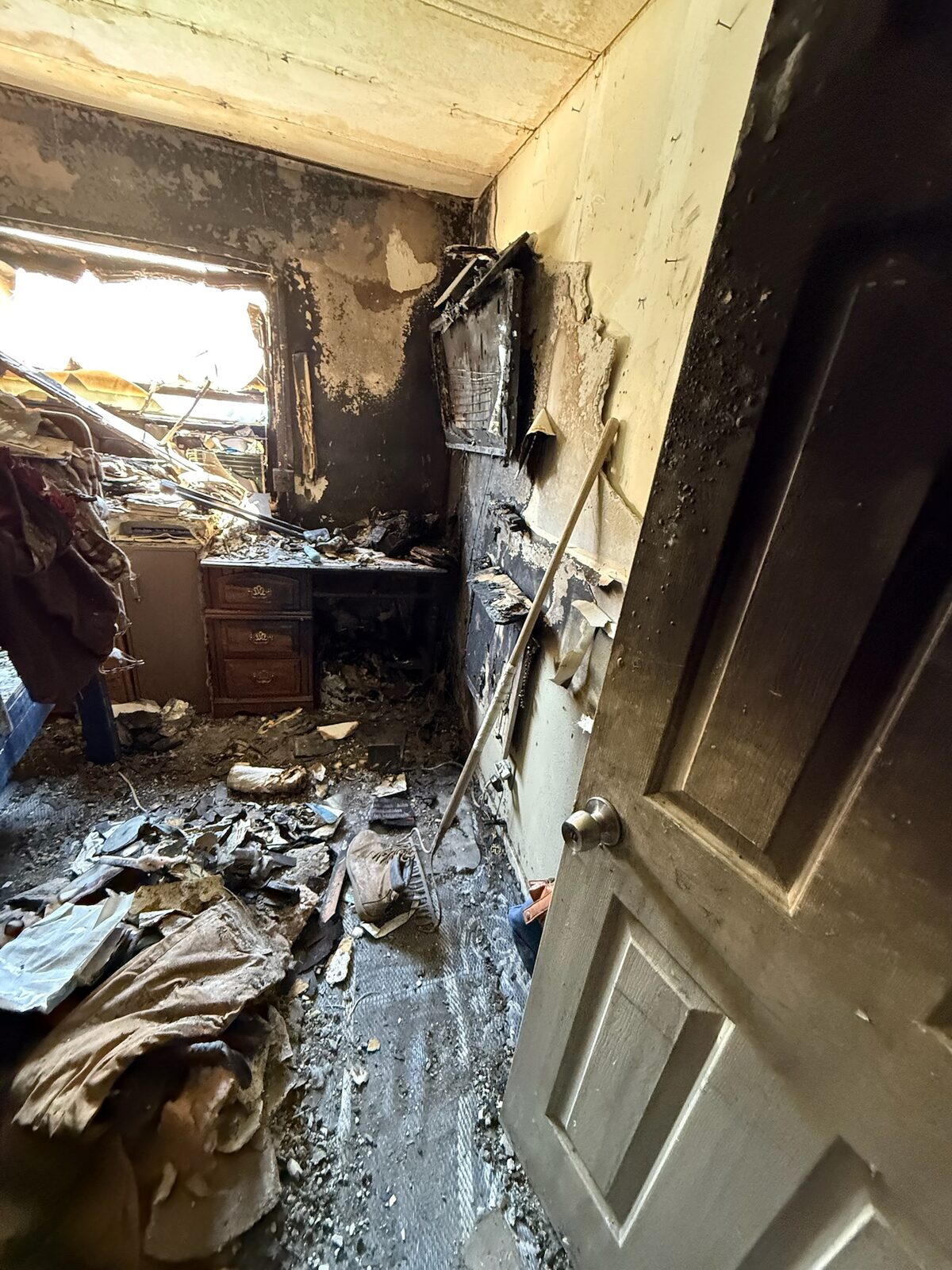 Bedroom interior with heavy fire and smoke damage to walls, ceiling and contents