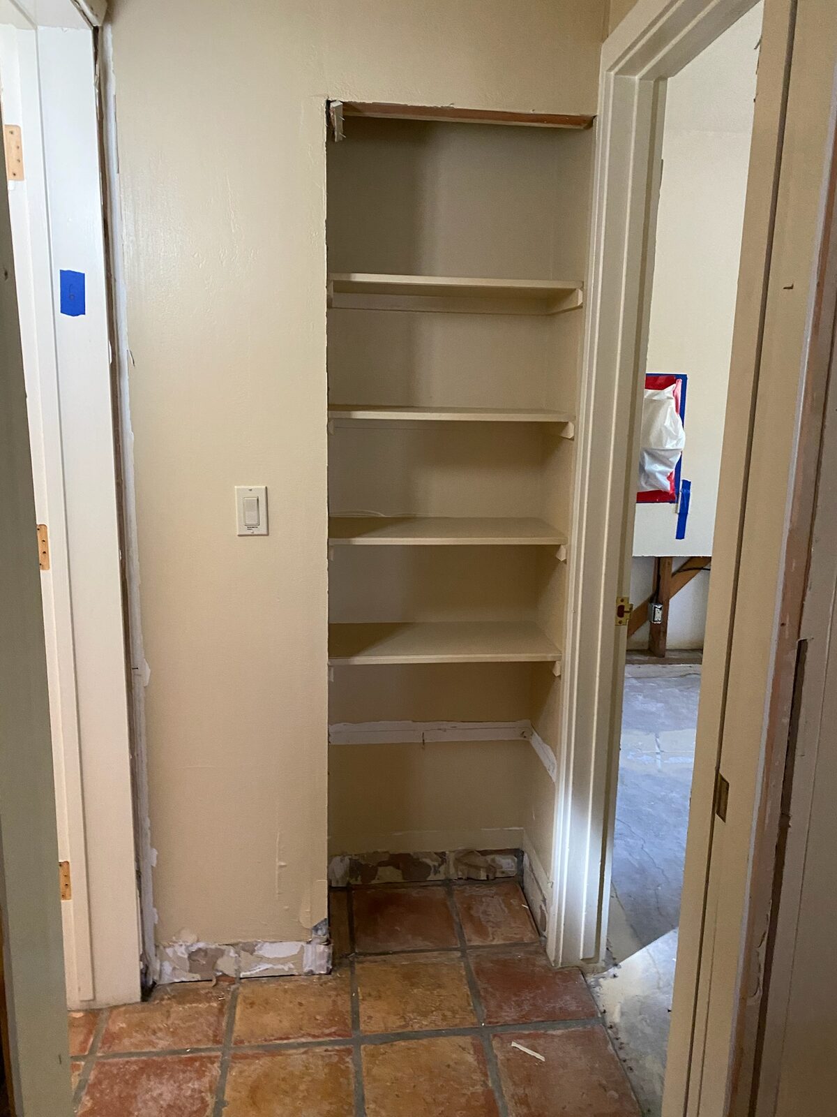 Built in closet shelves with baseboards removed and walls patched during repair