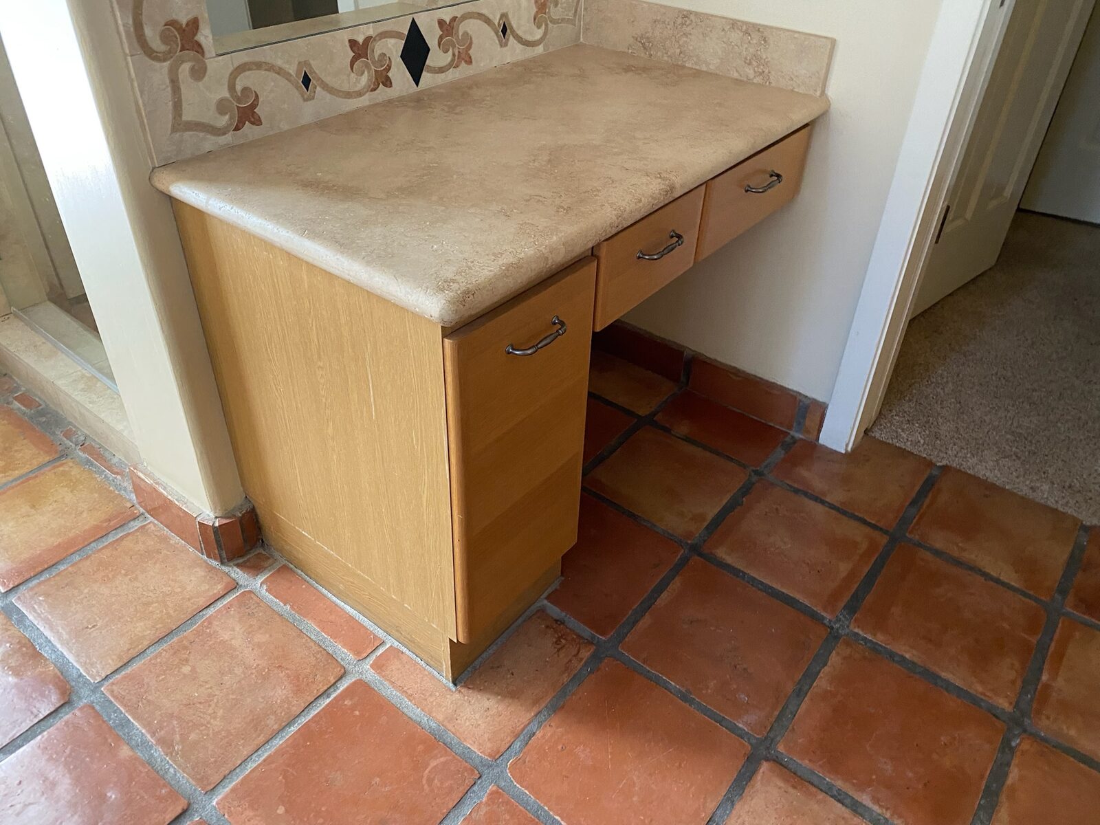 Built in vanity with stone countertop and decorative tile above a terracotta floor