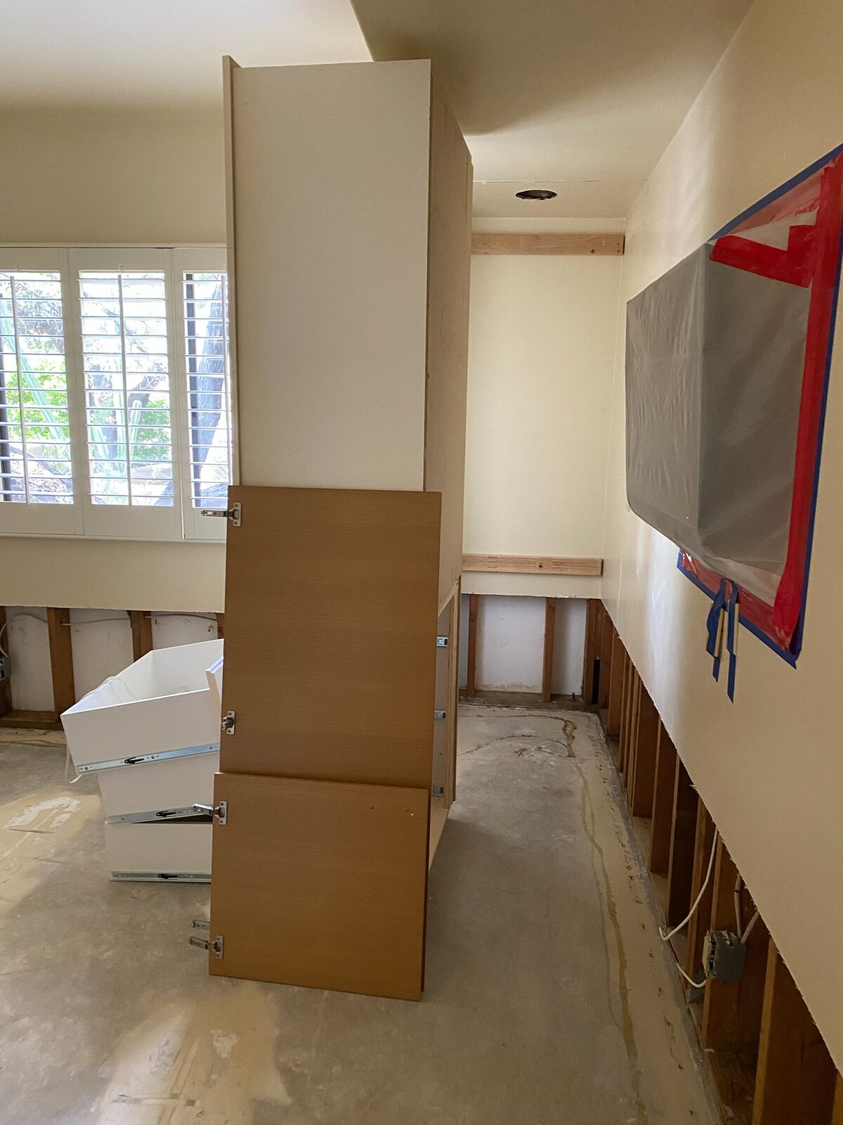 Cabinet tower being dismantled in a room with lower drywall removed for drying