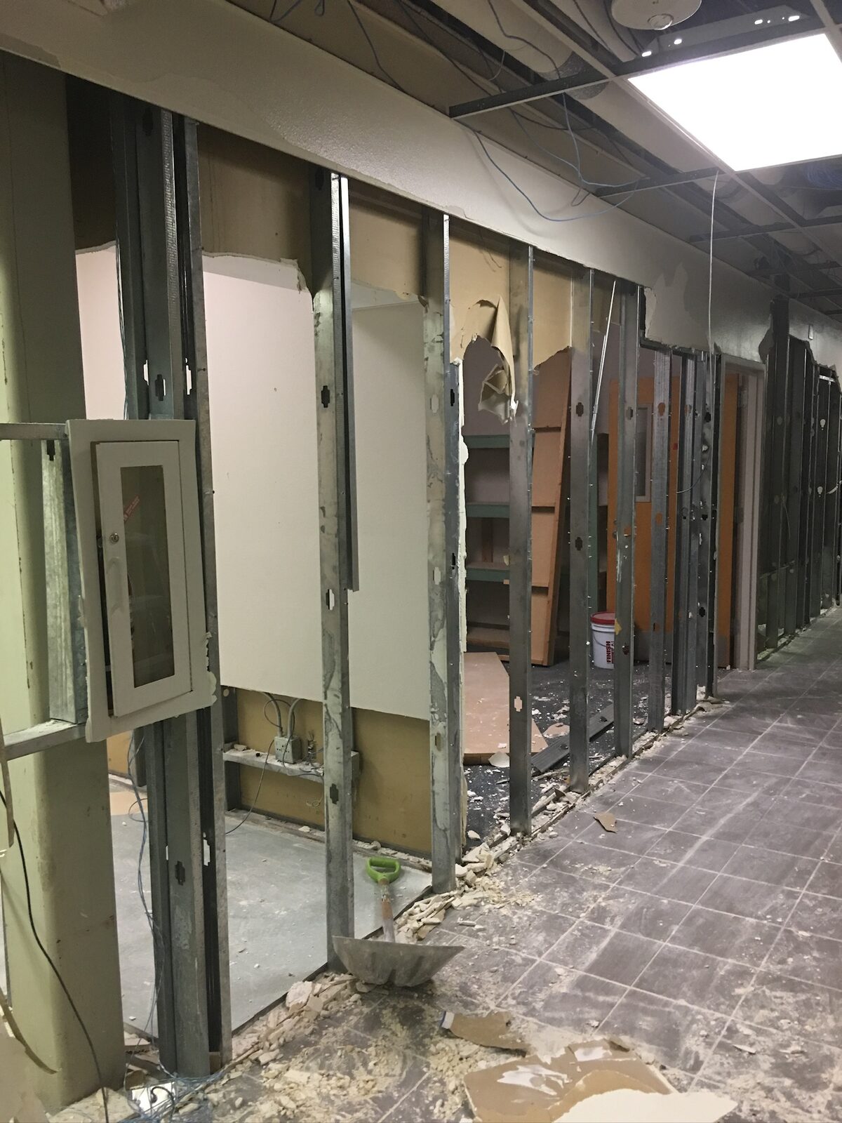Commercial hallway with drywall removed from metal stud framing during demolition