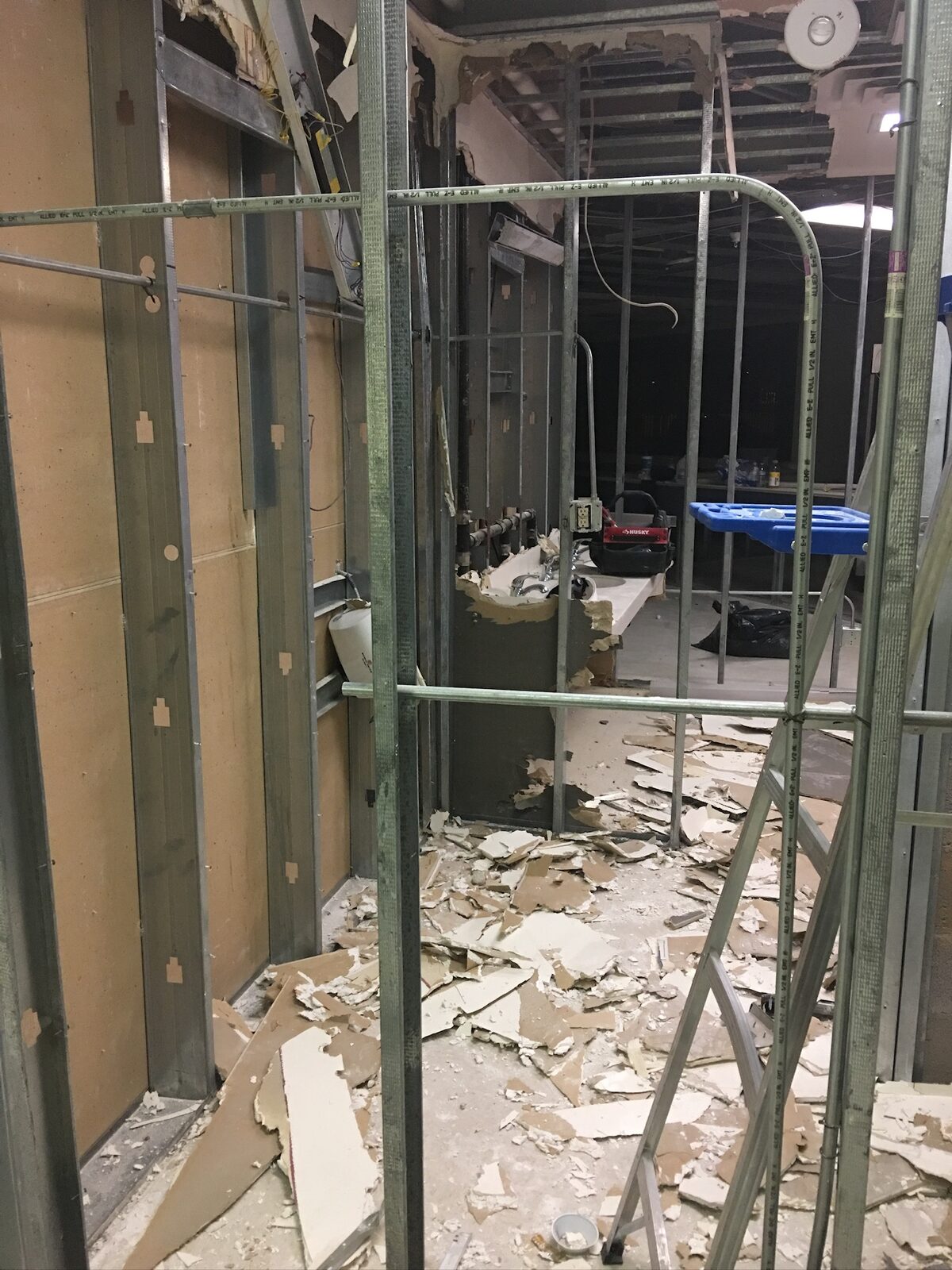 Commercial interior demolition with metal stud framing exposed and drywall debris on the floor