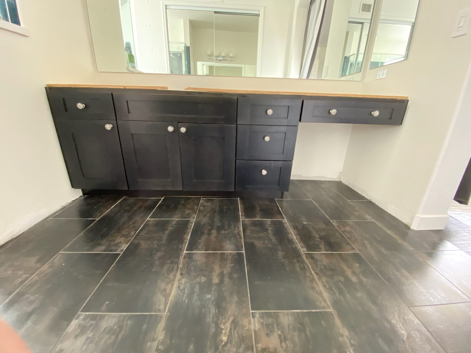 Dark shaker vanity cabinets installed below wall mirrors before countertop installation