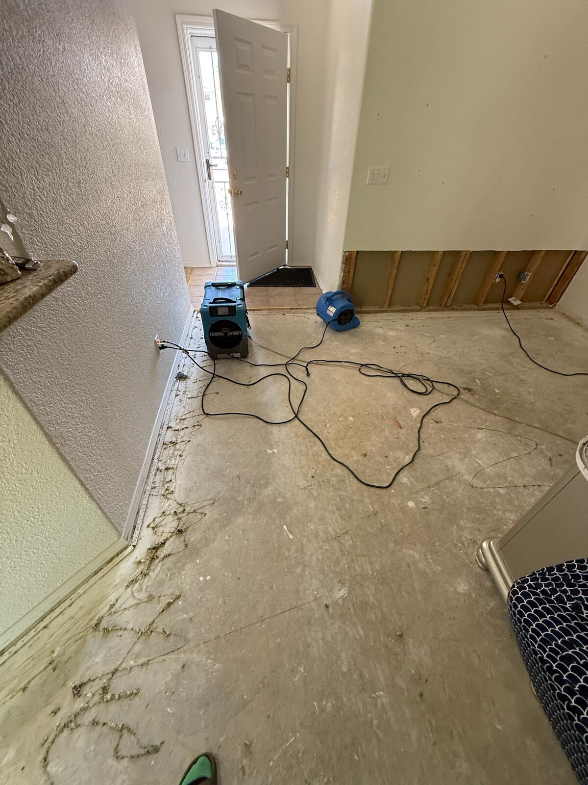 Dehumidifier and air mover drying an entry area with lower drywall removed
