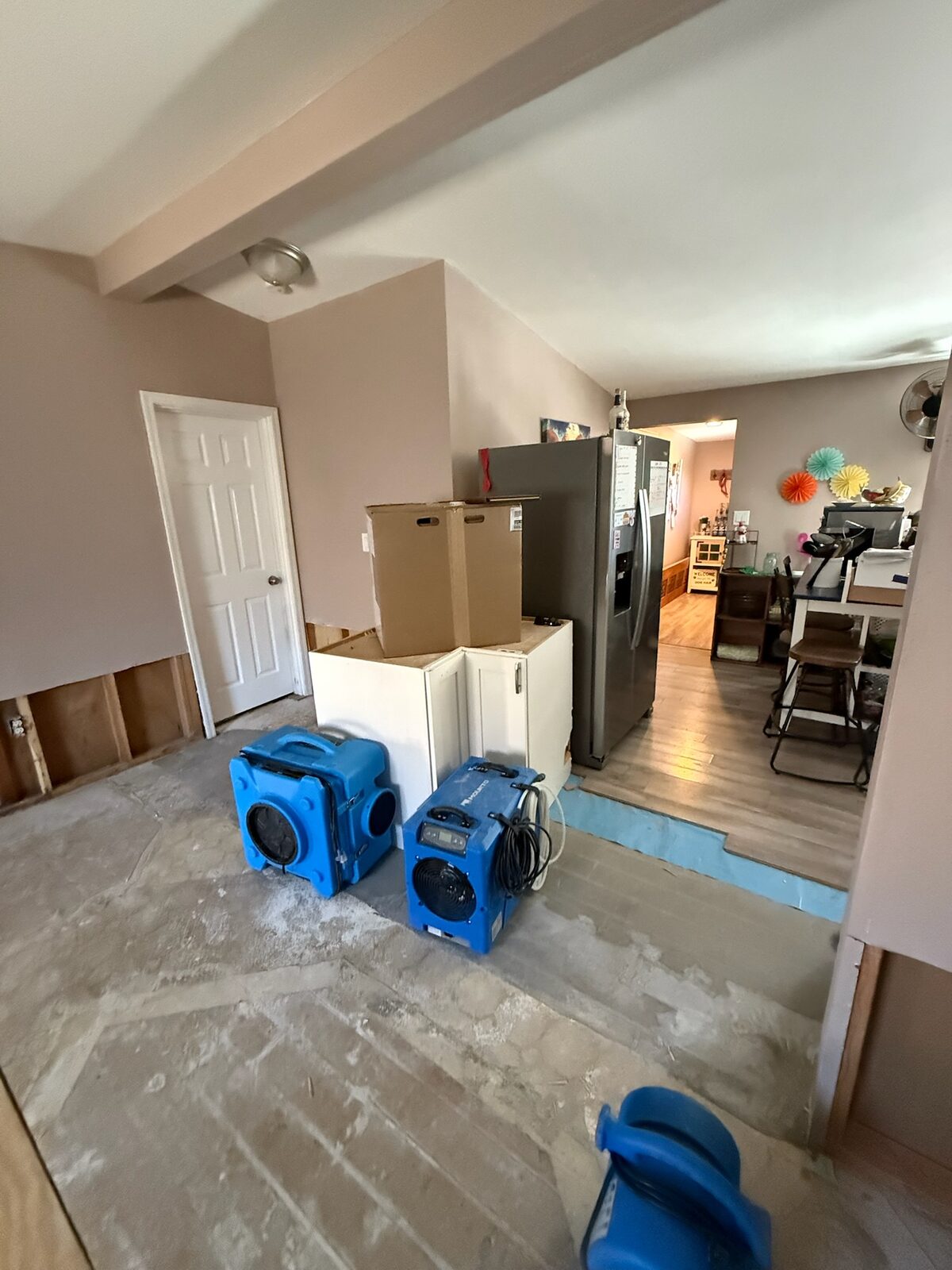 Dehumidifier and air scrubber drying a room with subfloor and lower walls exposed