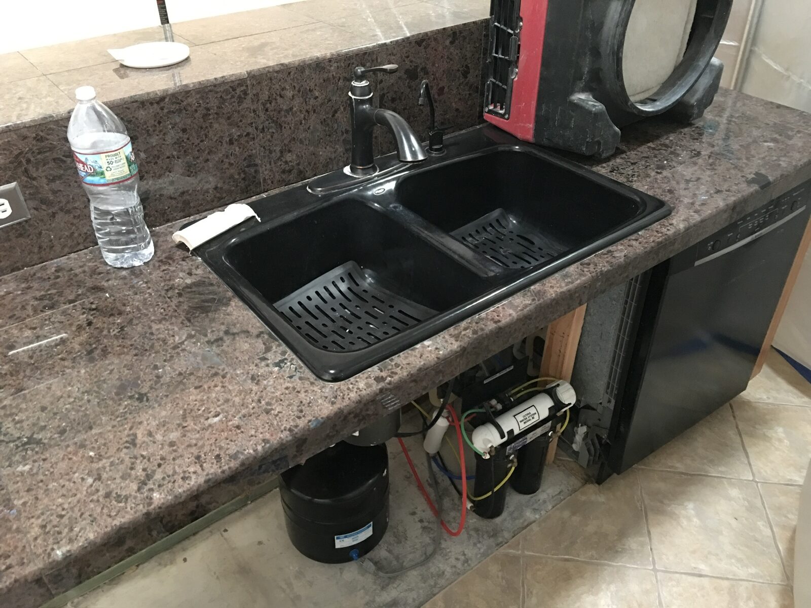 Double-bowl composite sink on granite tile counter with under-sink filtration exposed