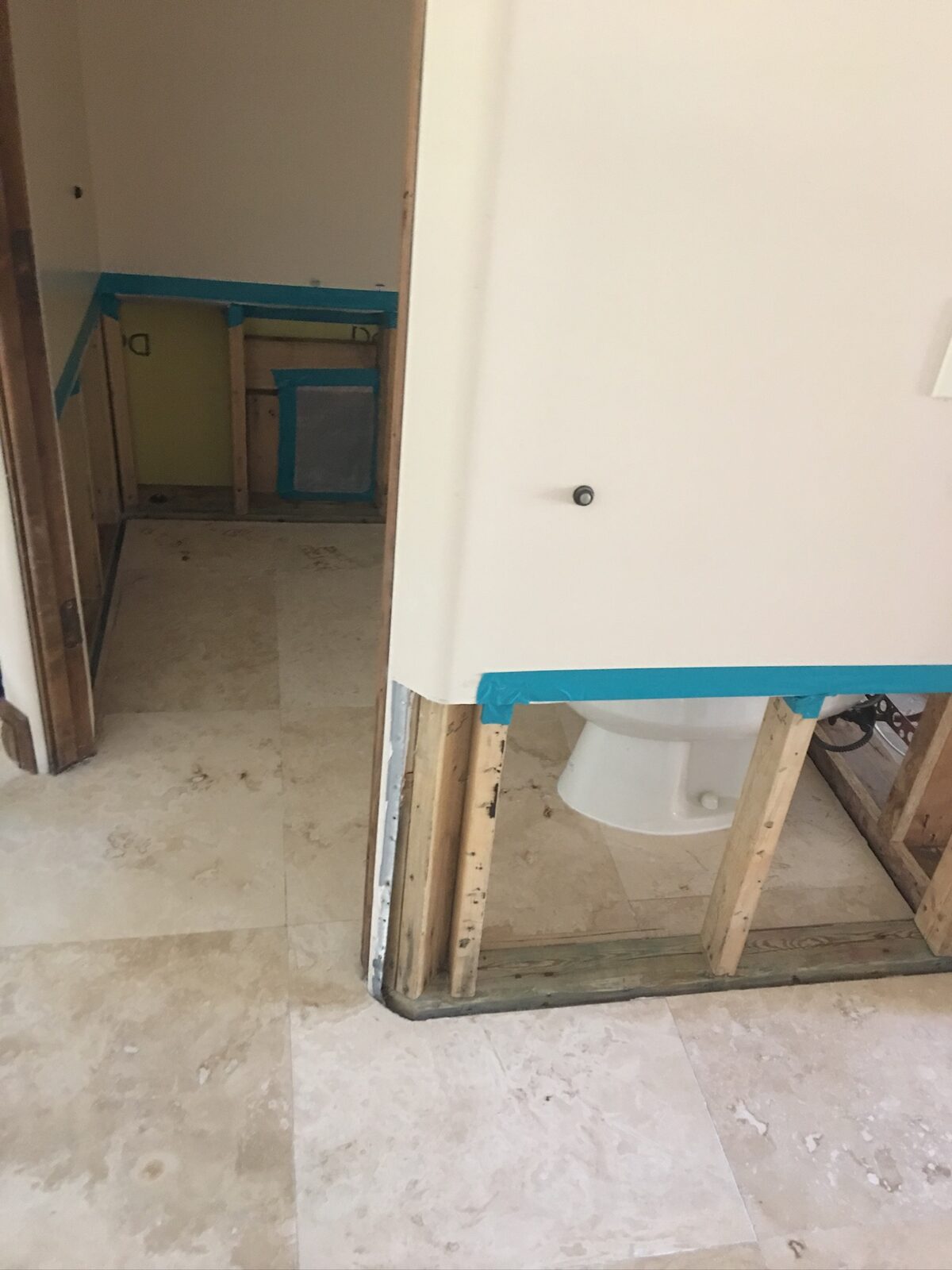 Flood cut walls with taped edges around a bathroom partition during water damage repair