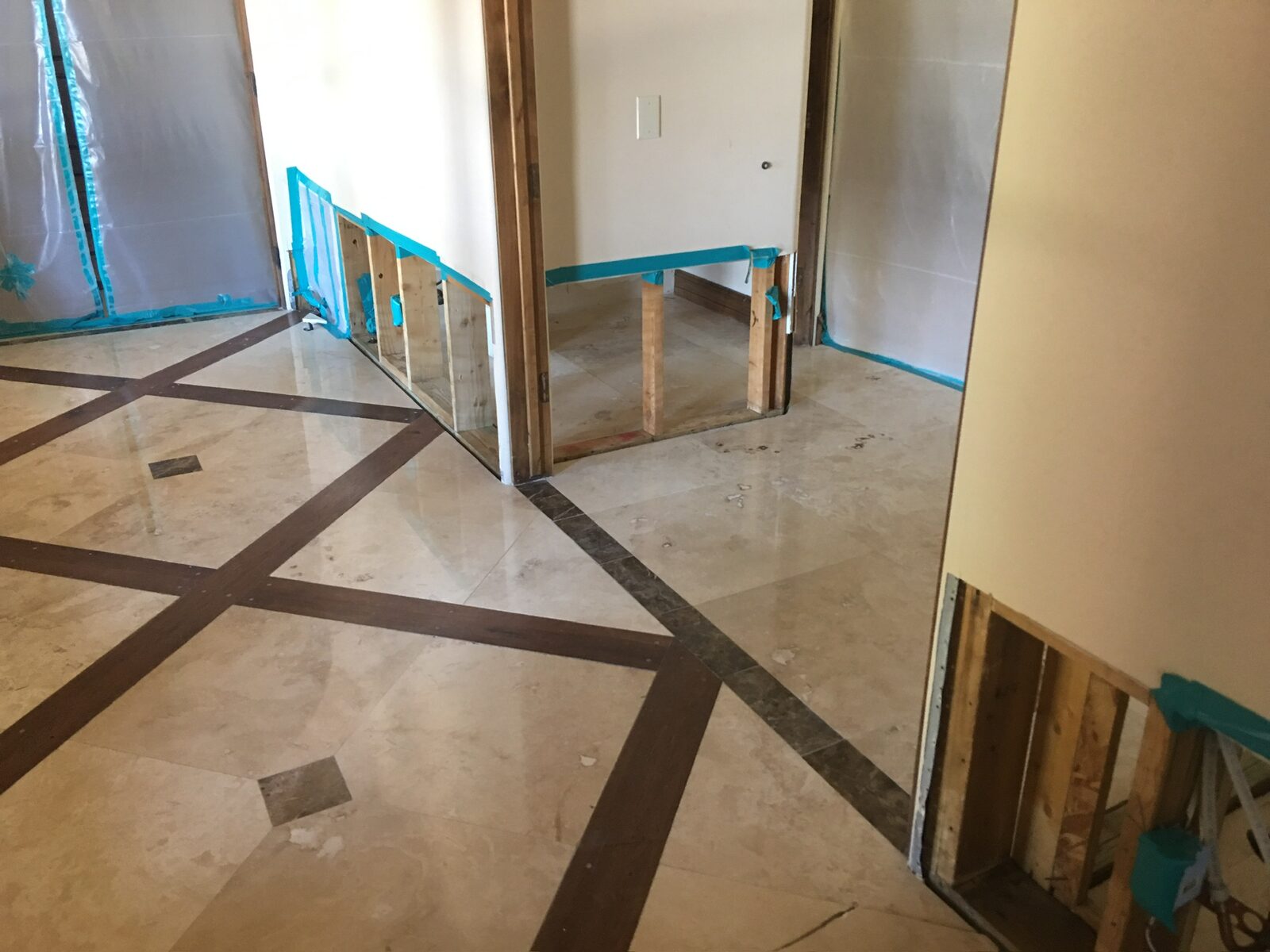 Flood cuts sealed with tape along walls above a stone floor with wood inlay borders