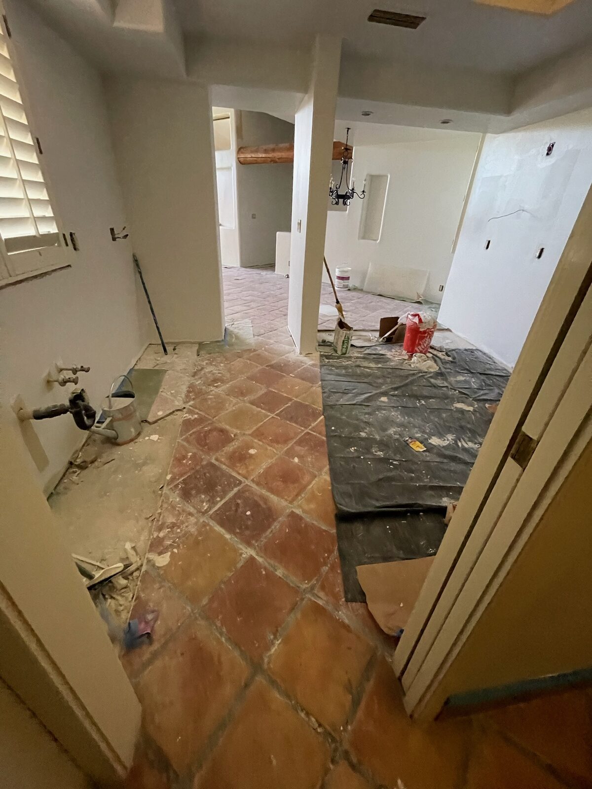 Freshly primed walls with drop cloths protecting a terracotta tile floor