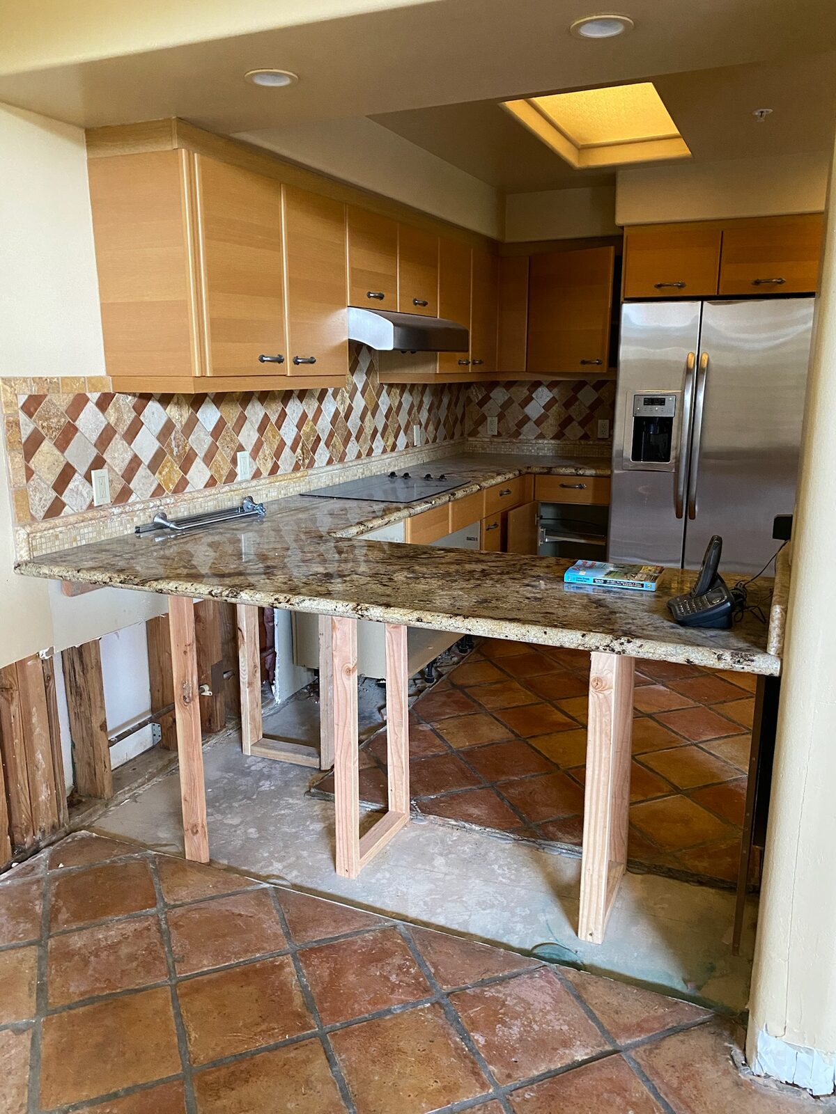 Granite countertop supported on temporary wood framing after base cabinets were removed