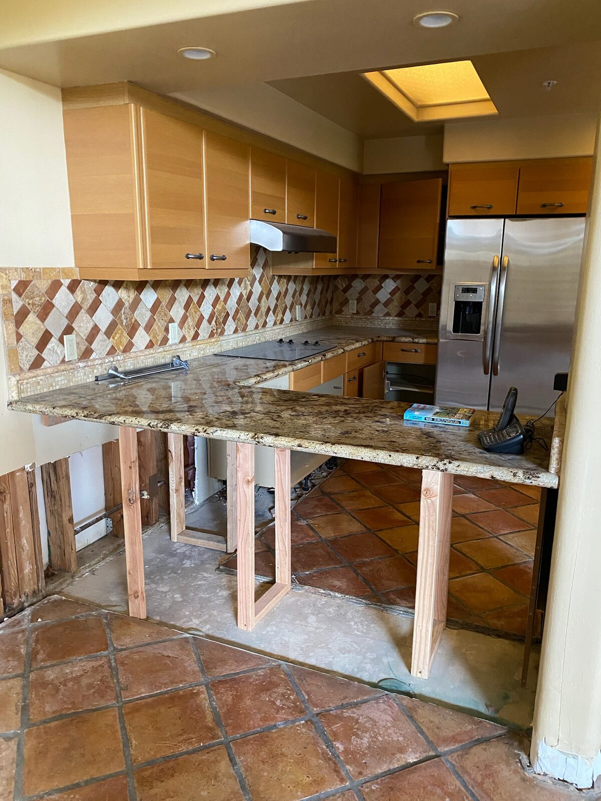 Granite countertops braced on temporary wood supports during cabinet replacement in a kitchen