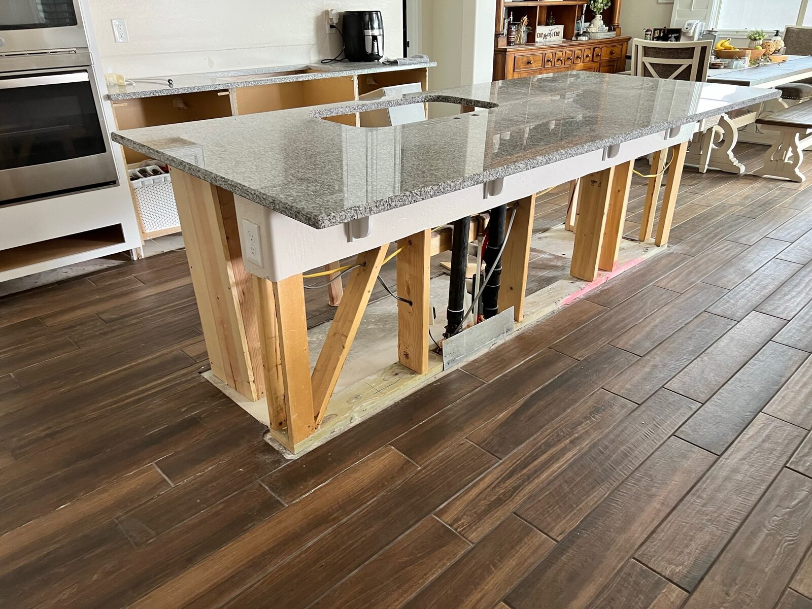 Granite island countertop supported by temporary wood bracing during cabinet replacement