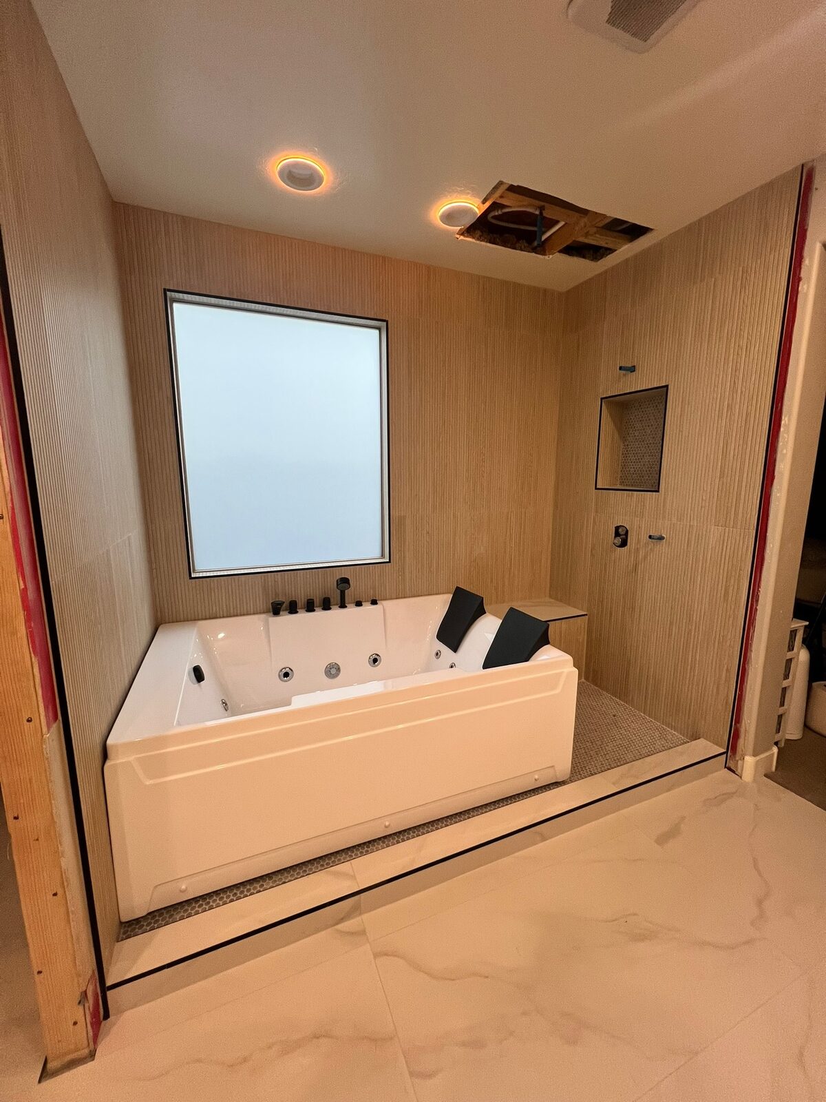 Jetted tub and fluted tile walls with a niche and bench in a bathroom remodel in progress
