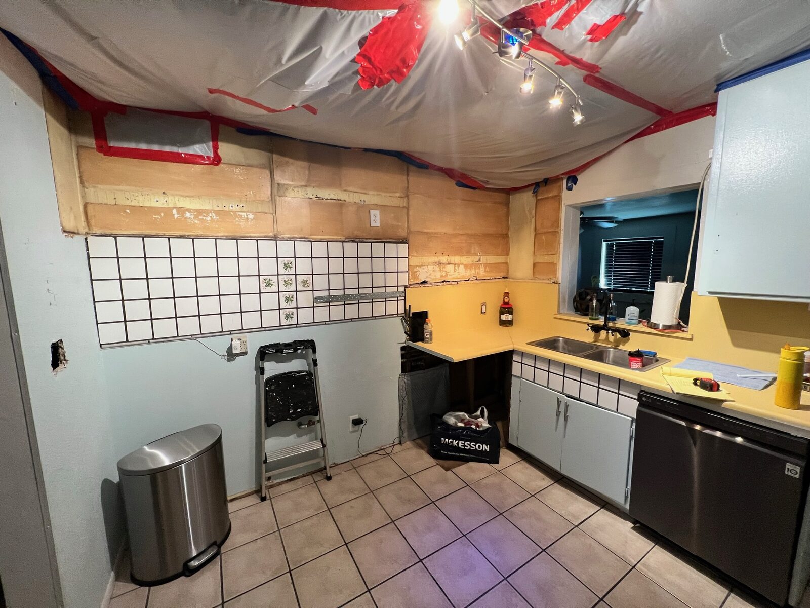 Kitchen with ceiling containment plastic and upper wall surfaces stripped for repair