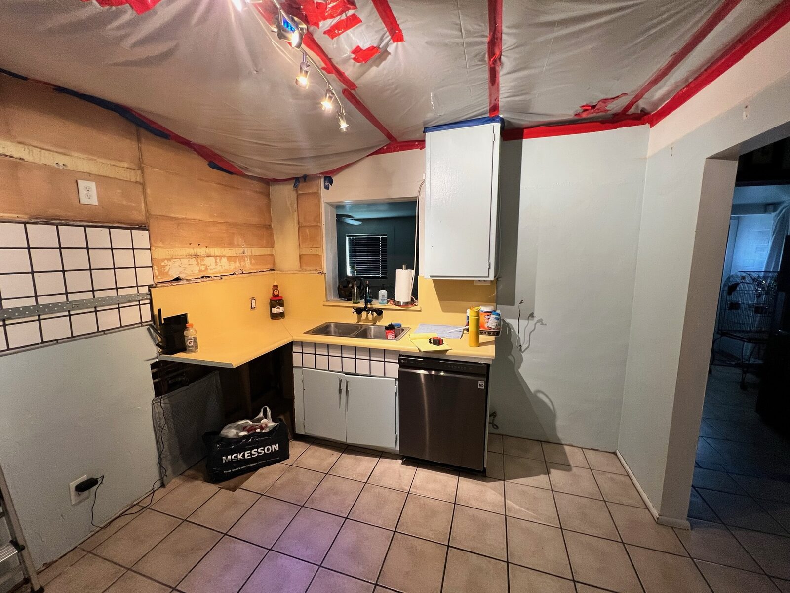 Kitchen with ceiling plastic sheeting and partial backsplash removal during restoration