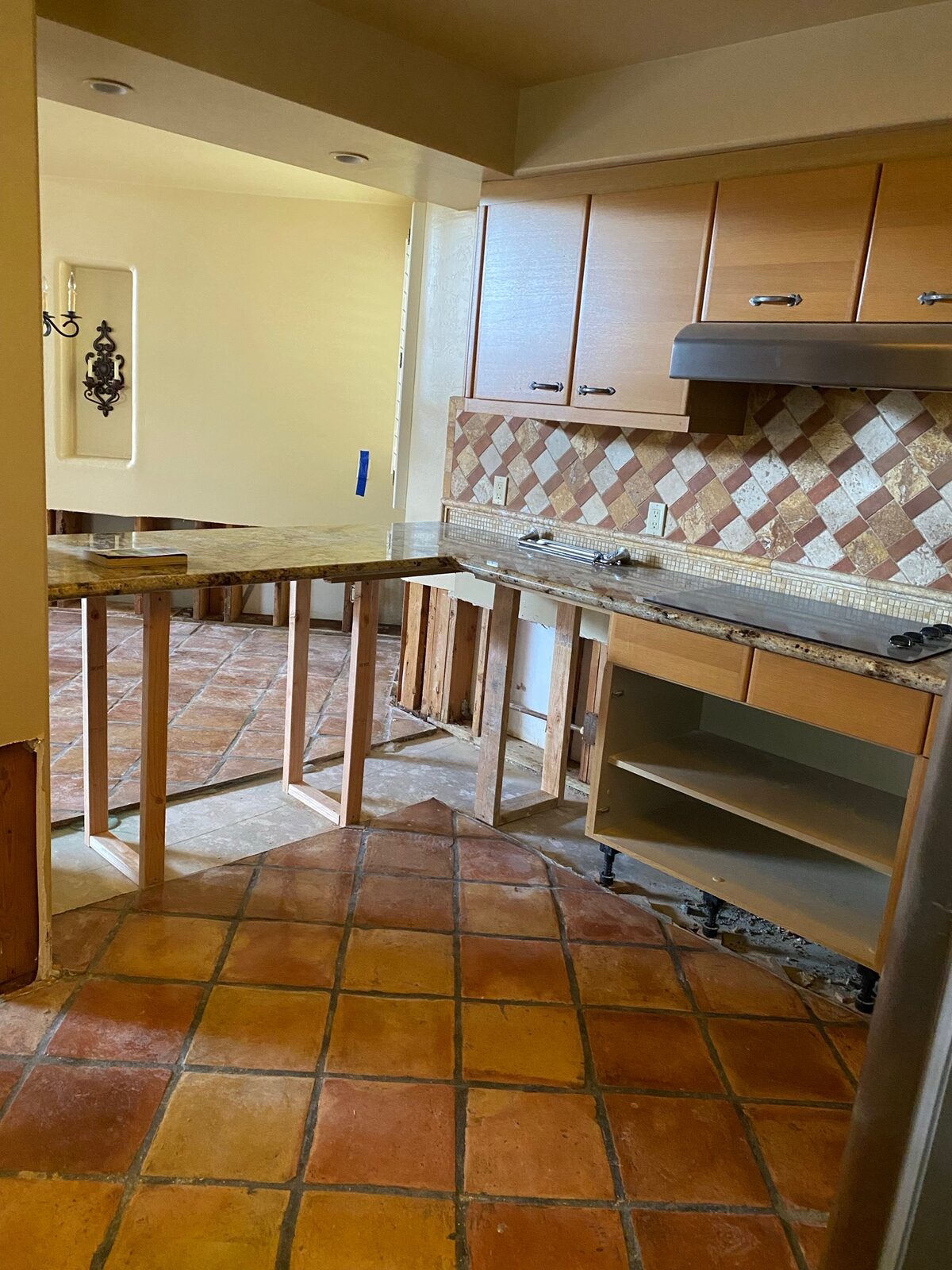 Kitchen counters braced on temporary wood supports over saltillo tile during cabinet repair