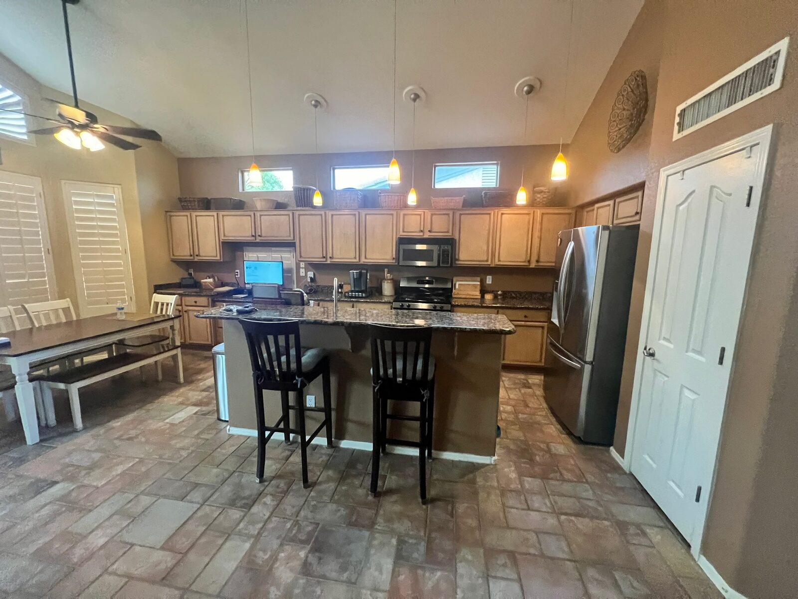 Kitchen with granite topped island, pendant lights and stainless refrigerator