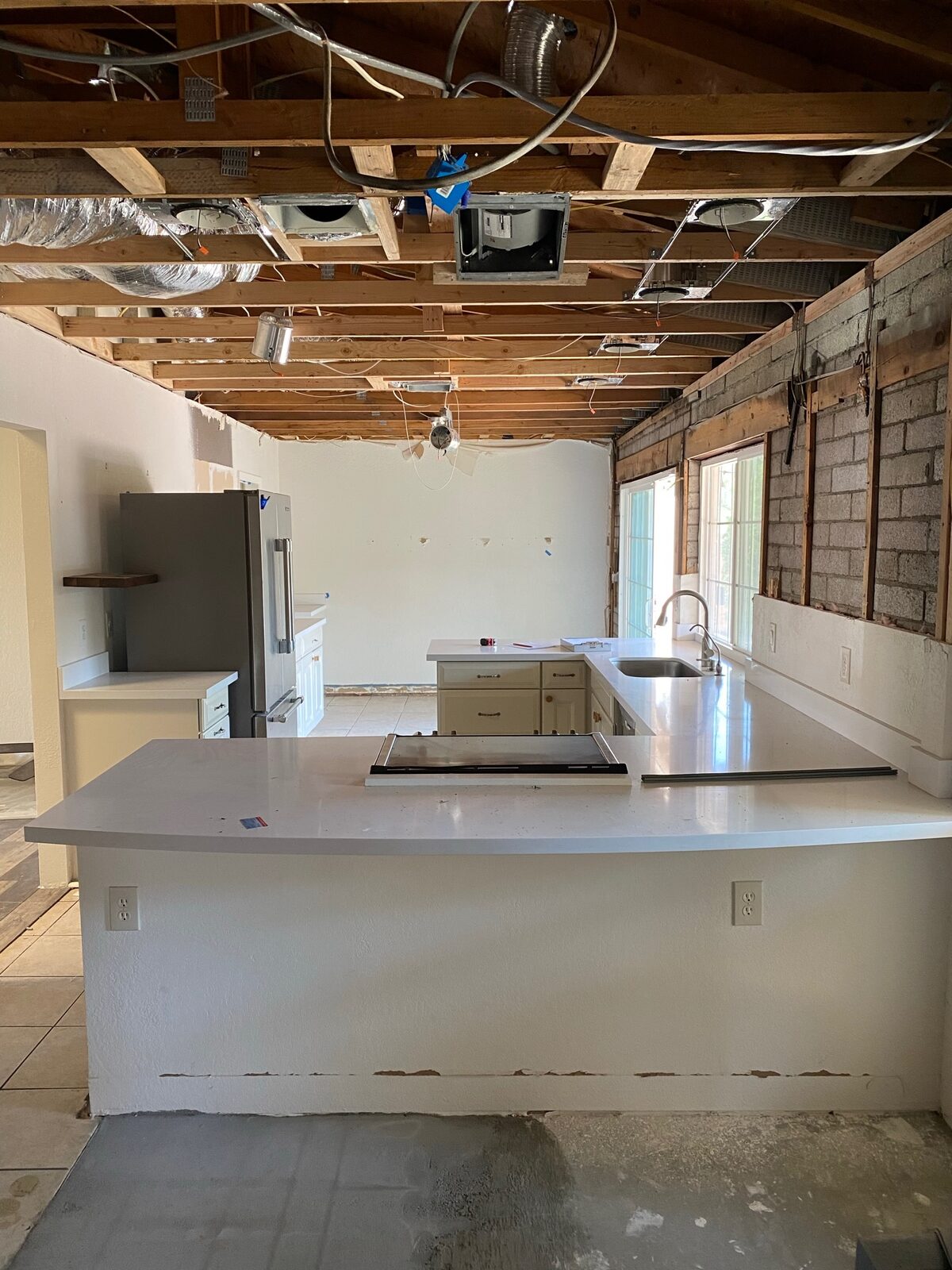 Kitchen mid remodel with new quartz countertops below an open joist ceiling