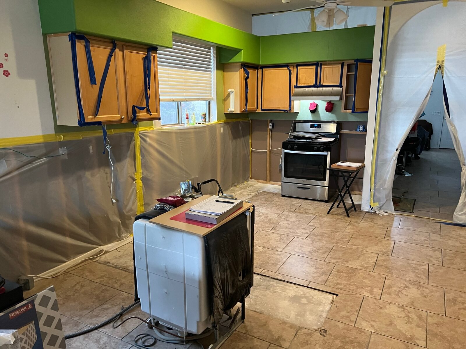Kitchen prepared with plastic containment sheeting taped over lower walls and cabinets