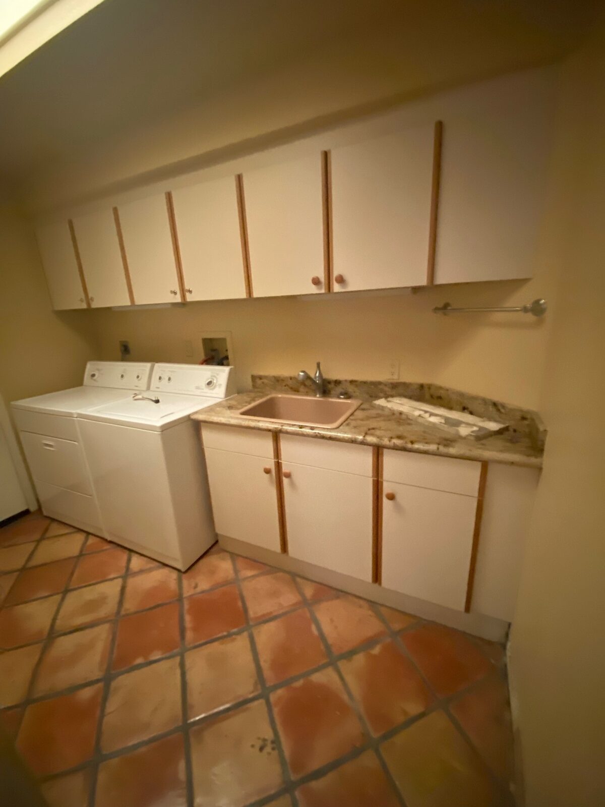 Laundry room with granite countertop, utility sink, white cabinets and saltillo tile floor