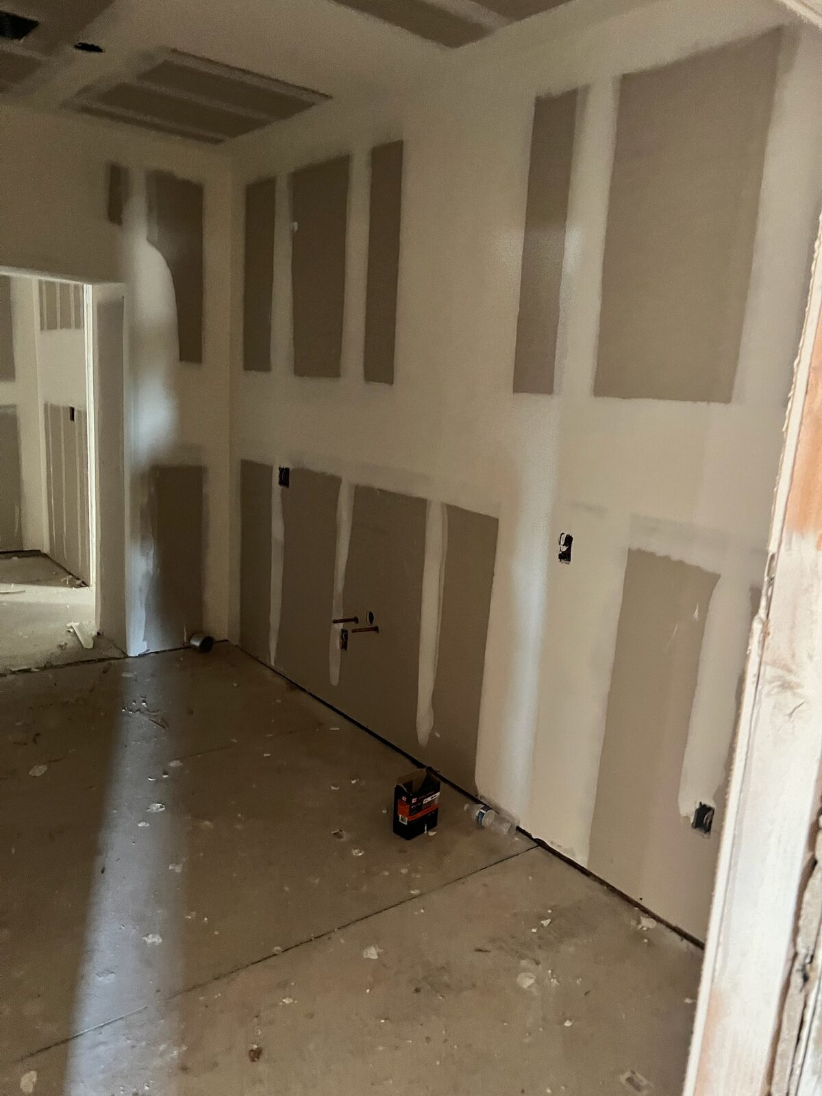 New drywall hung with seams taped and mudded in a room under reconstruction