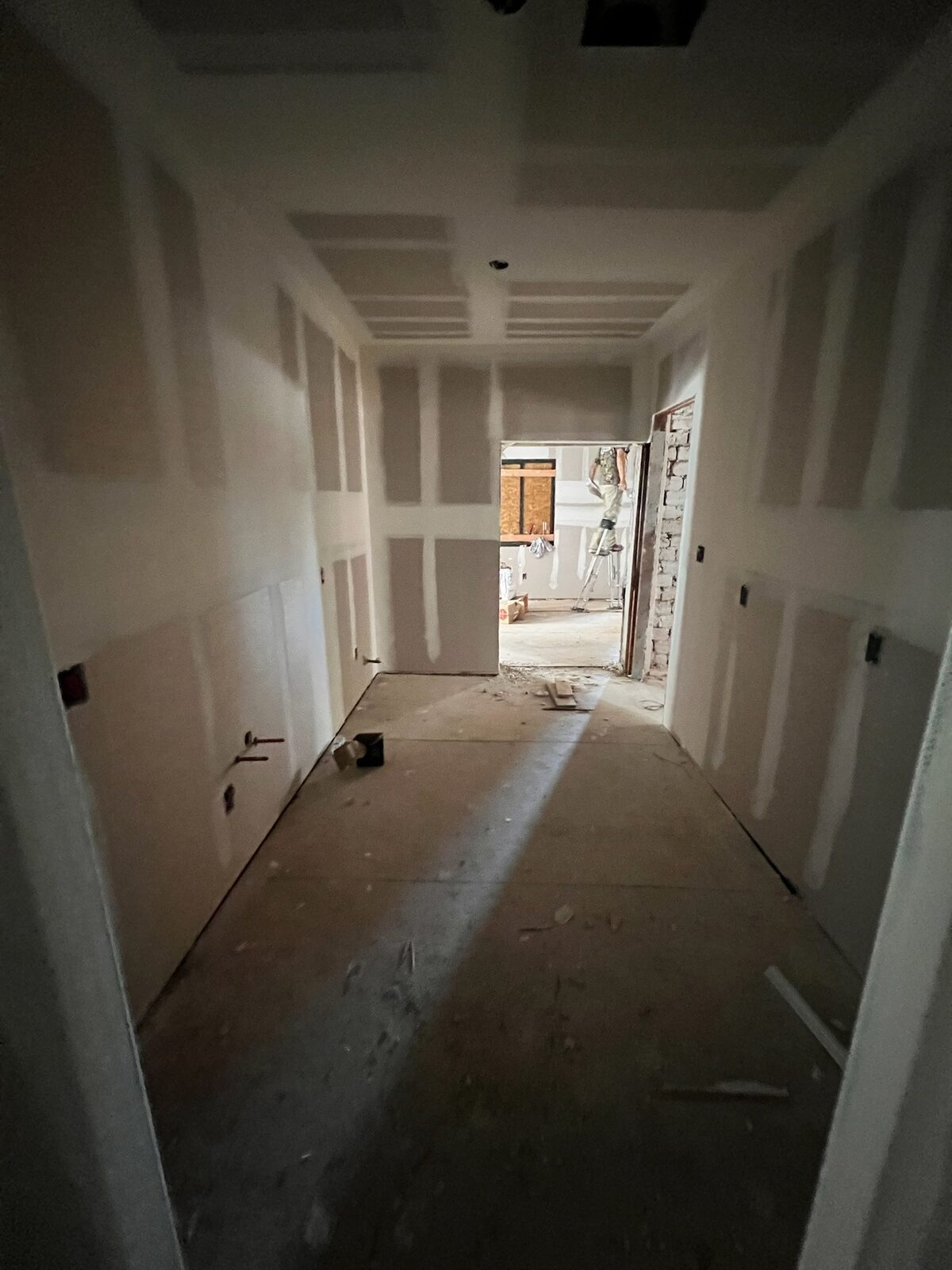 New drywall hung and taped in a hallway during reconstruction
