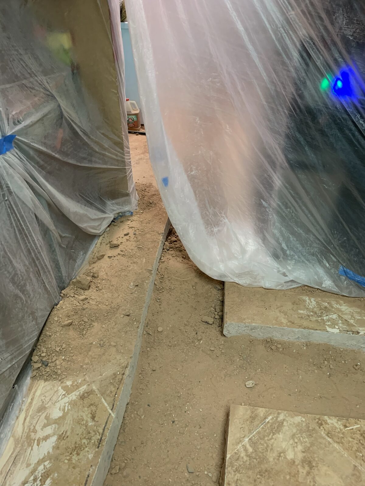 Plastic containment sheeting hung around a work area with dust and debris on the floor