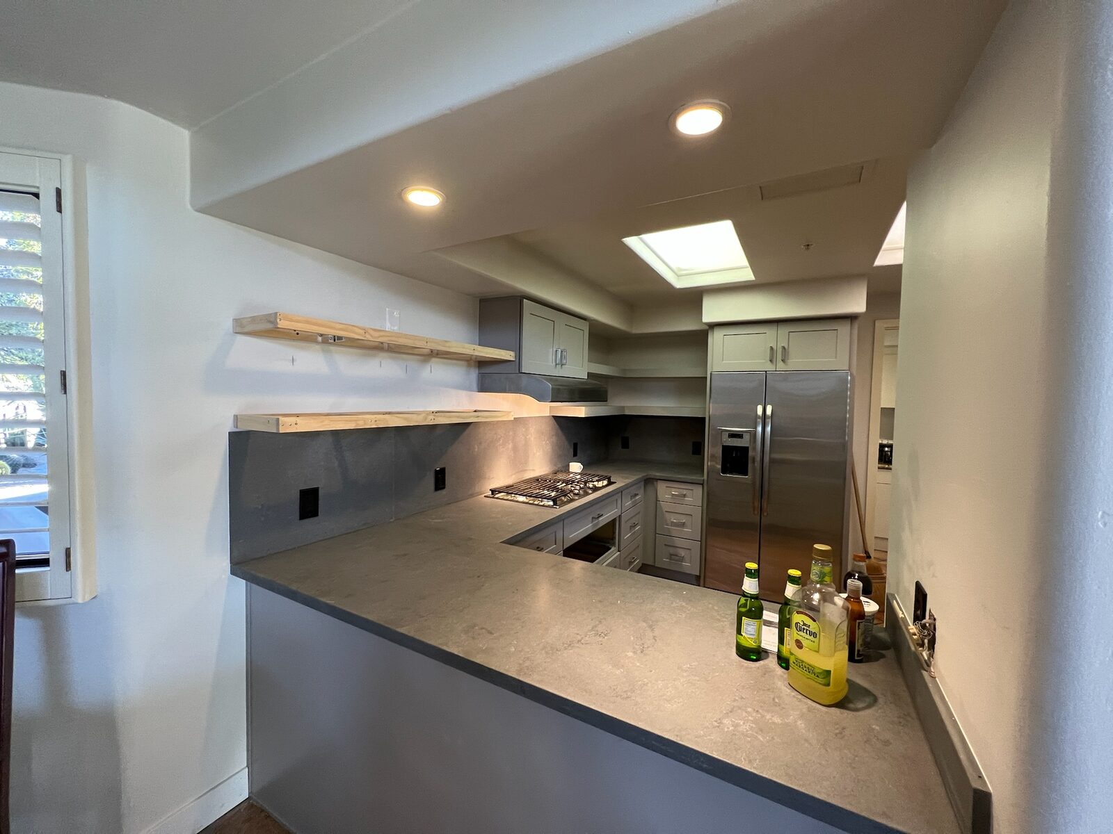 Remodeled kitchen with gray quartz counters, shaker cabinets, gas cooktop, and stainless refrigerator