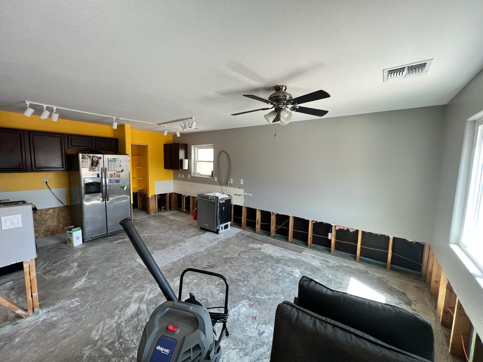 Room with lower drywall removed around the perimeter and flooring stripped to concrete