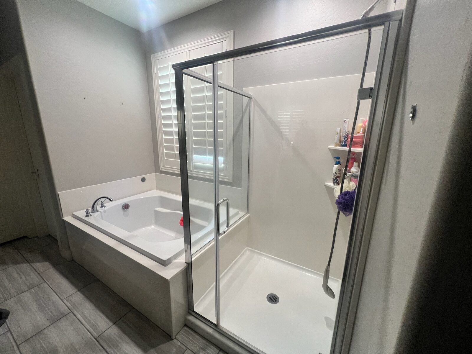 Soaking tub and glass-enclosed shower with white surround in a finished bathroom