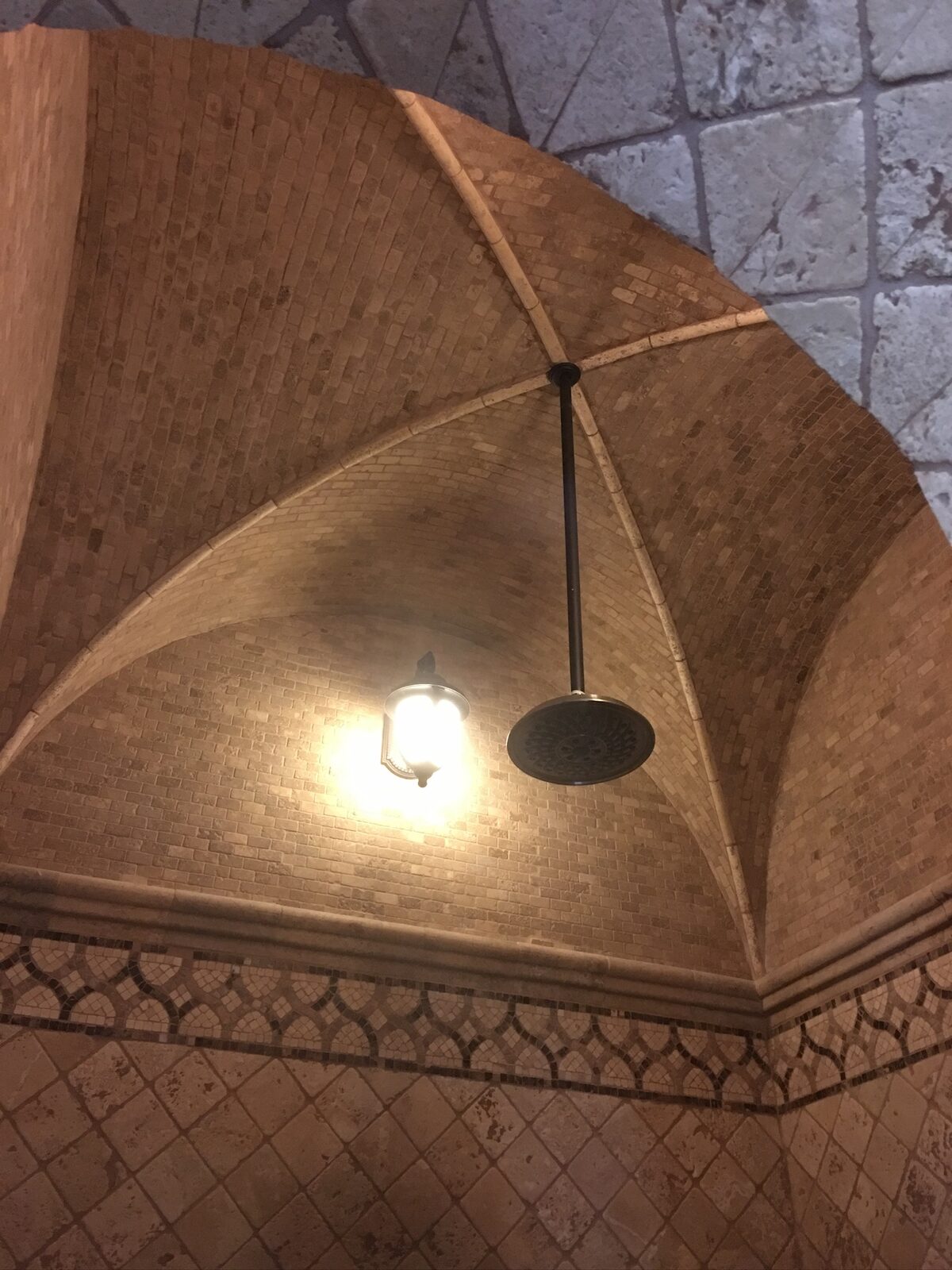 Tiled groin vault shower ceiling with stone mosaic bands, a pendant light and rain shower head