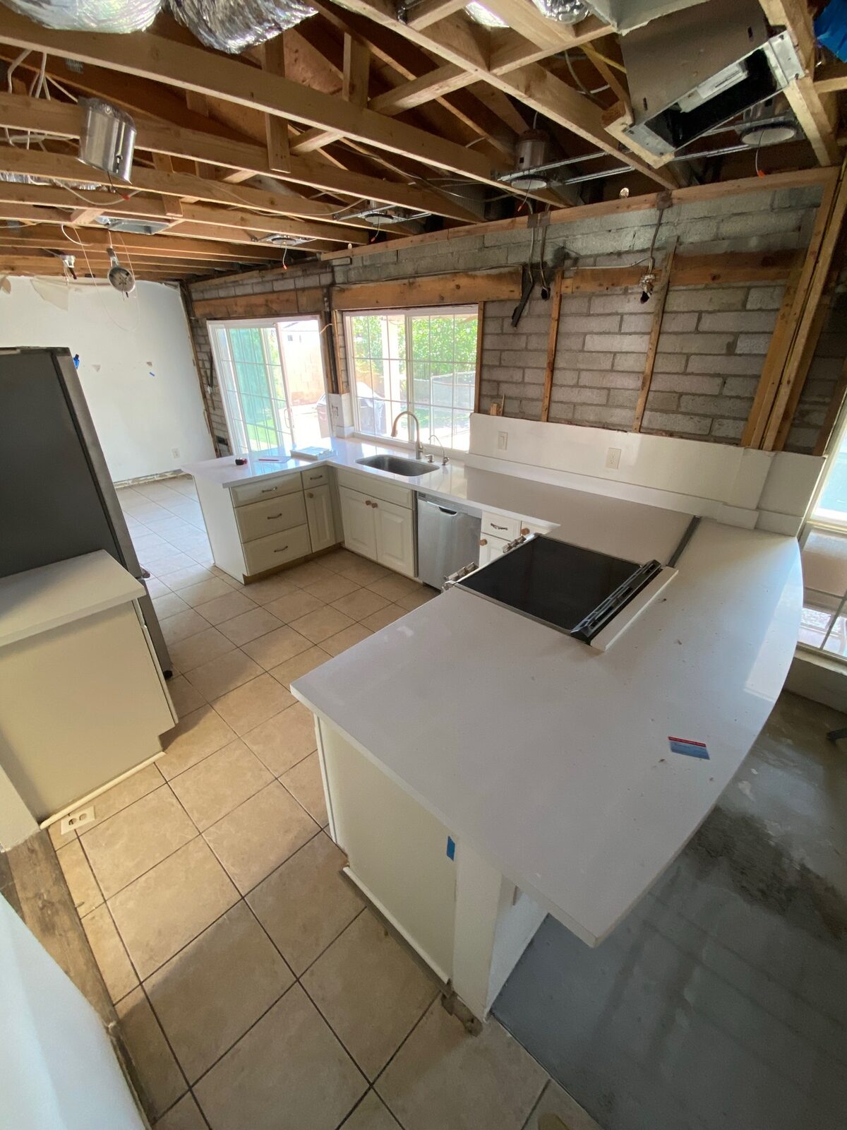 White quartz countertops and sink installed in a kitchen opened to ceiling joists and block walls