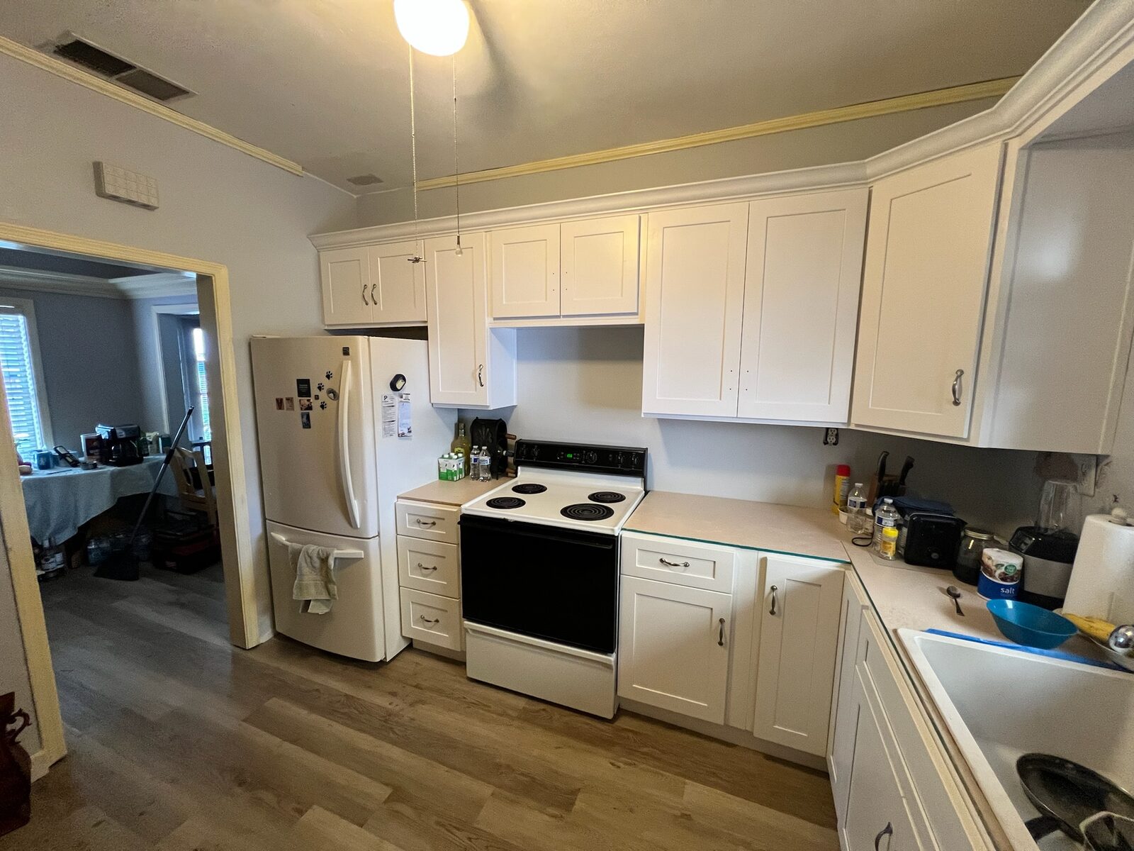 White shaker cabinets with crown molding and an electric range in a finished kitchen