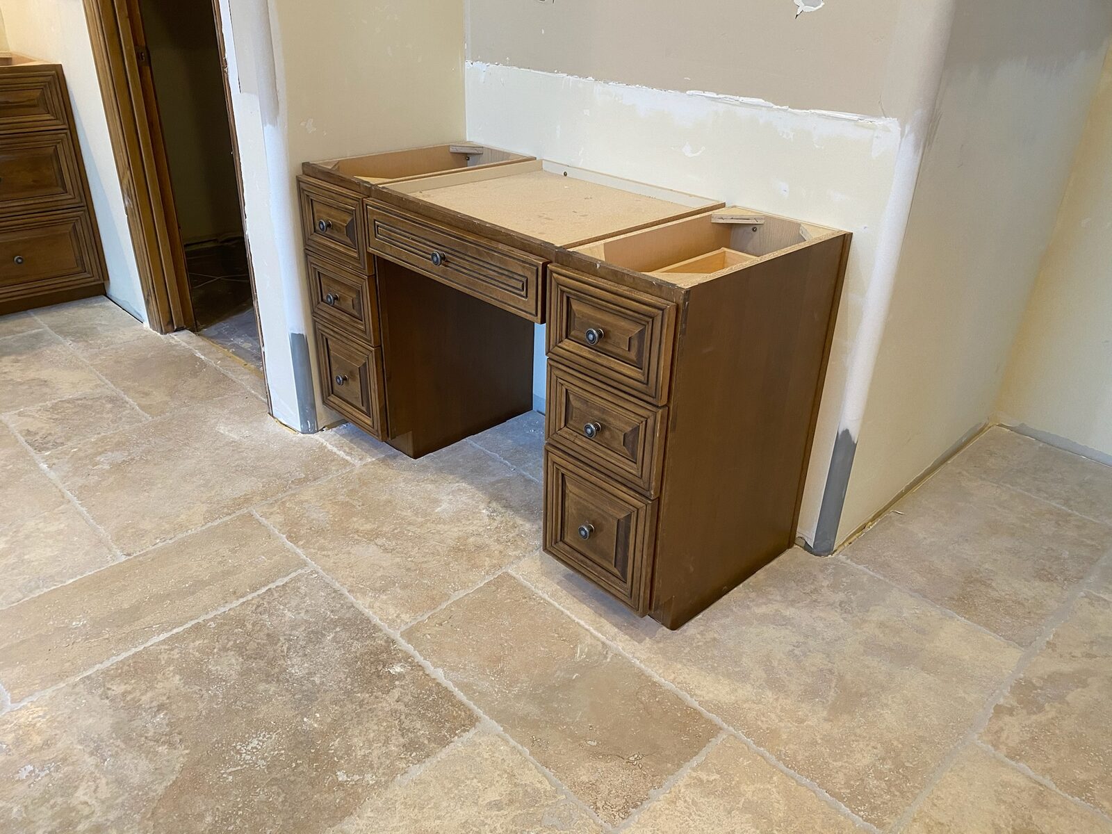 Wood vanity cabinet bases set in place on travertine tile before countertop installation