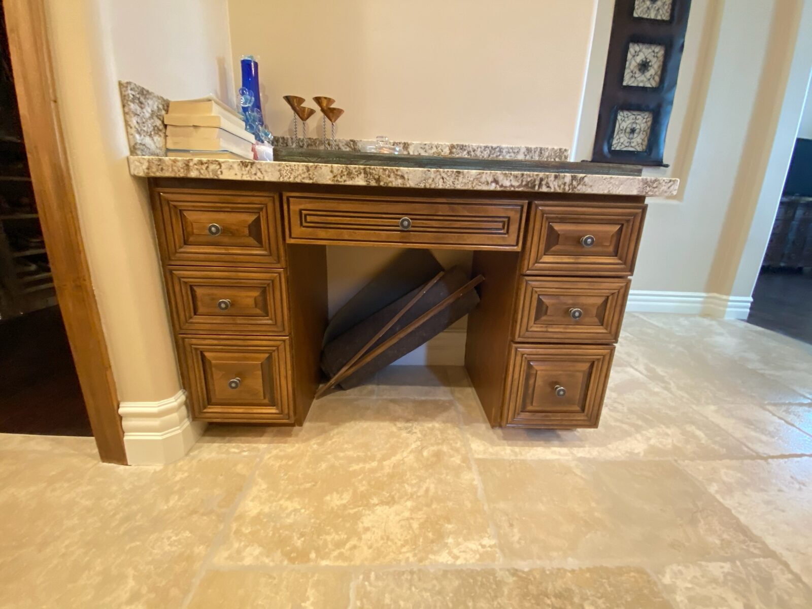 Wood vanity with knee space and a granite top installed over travertine tile