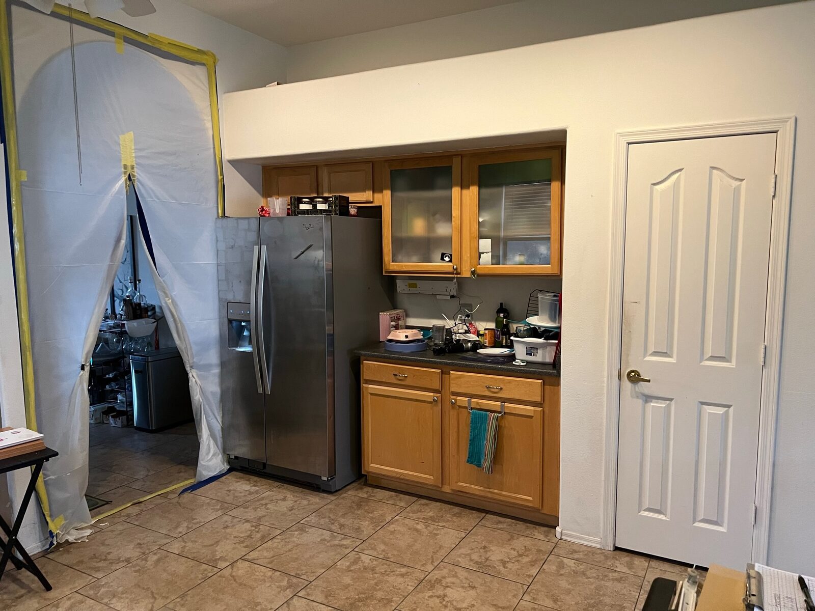 Zippered plastic containment doorway set up beside a kitchen refrigerator